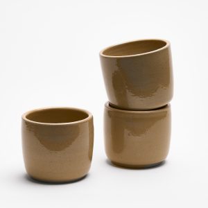 Drei beige Espressotassen aus Steinzeug. Aufeinander gestapelt. Seitlich fotografiert